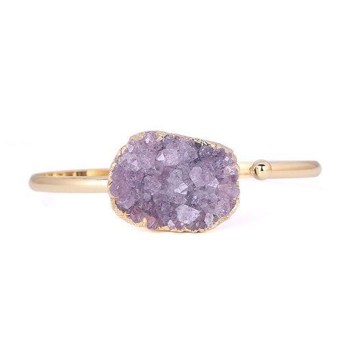 Ring with purple geode stone and gold band on a white background