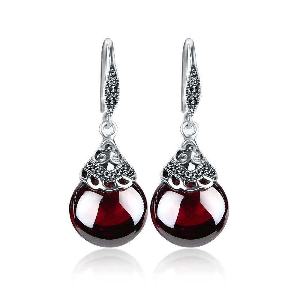 Pair of red teardrop earrings with silver hooks on a white background
