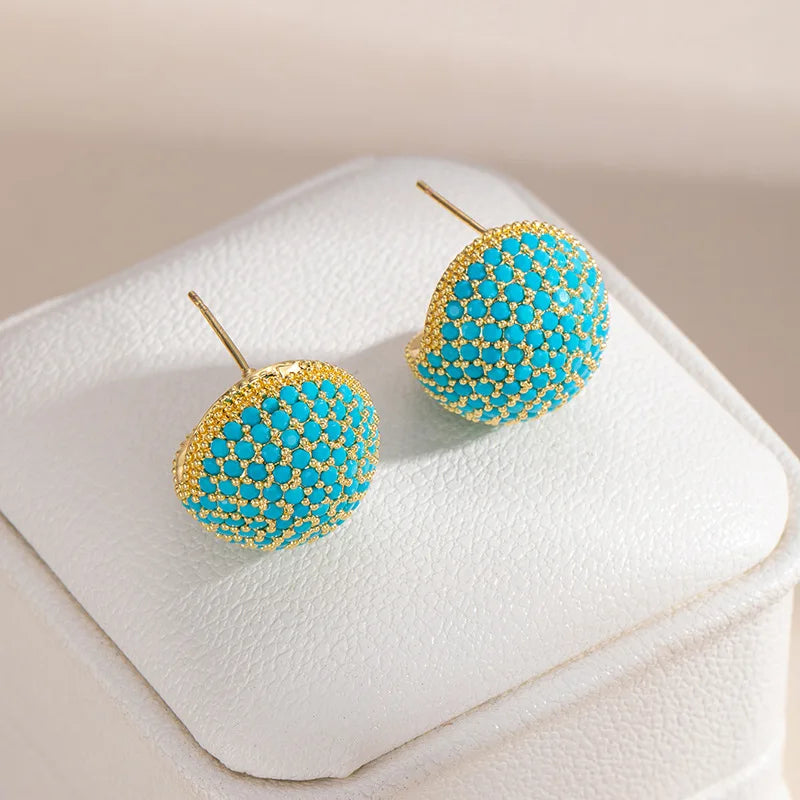 A pair of A close-up of a ring with a large oval turquoise stone design, displayed on a white textured jewelry box.