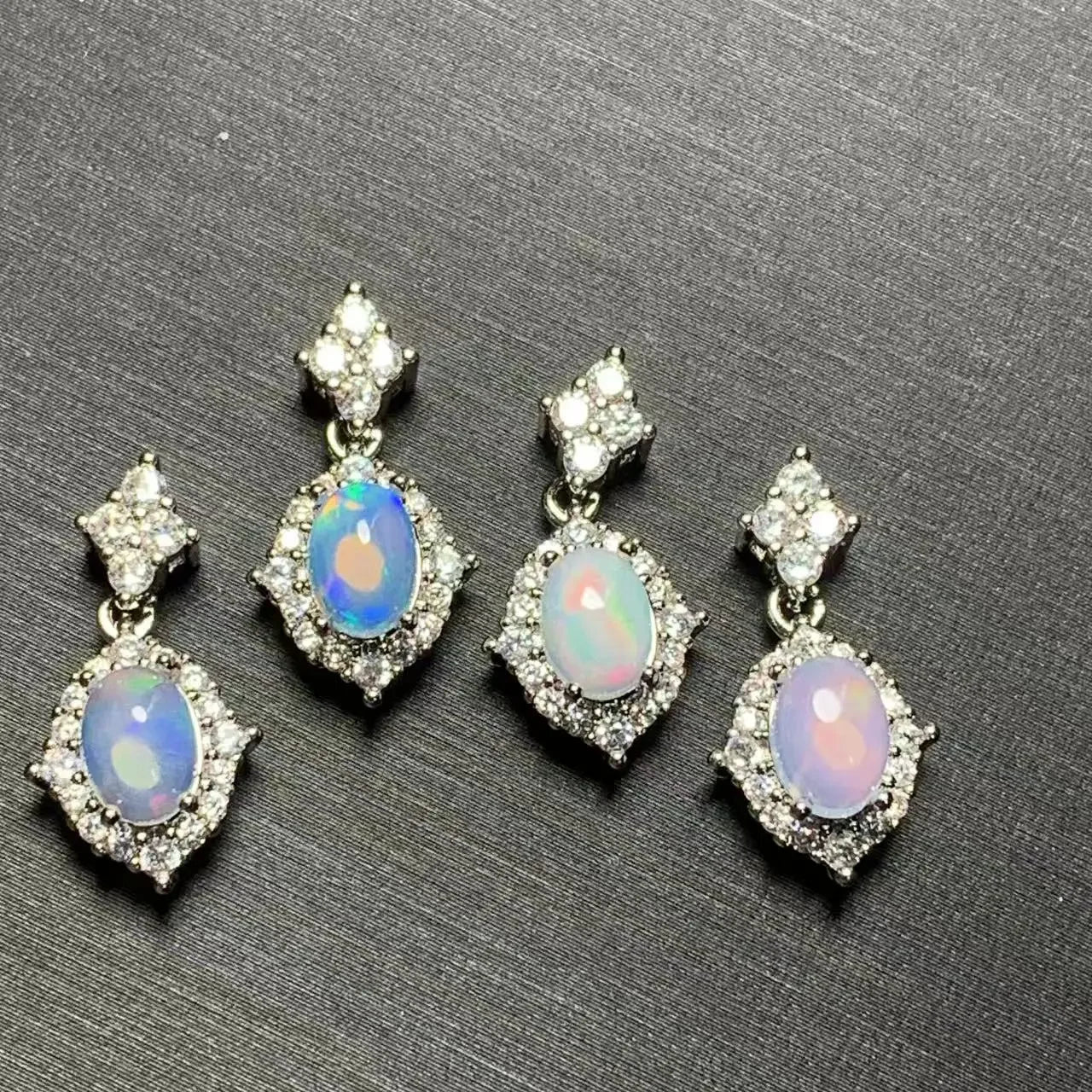 Set of four opal earrings with clear stones on a gray background