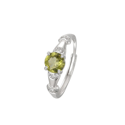 A silver-tone ring featuring a round olive-green center stone and small clear accent stones, shown on a plain white background.