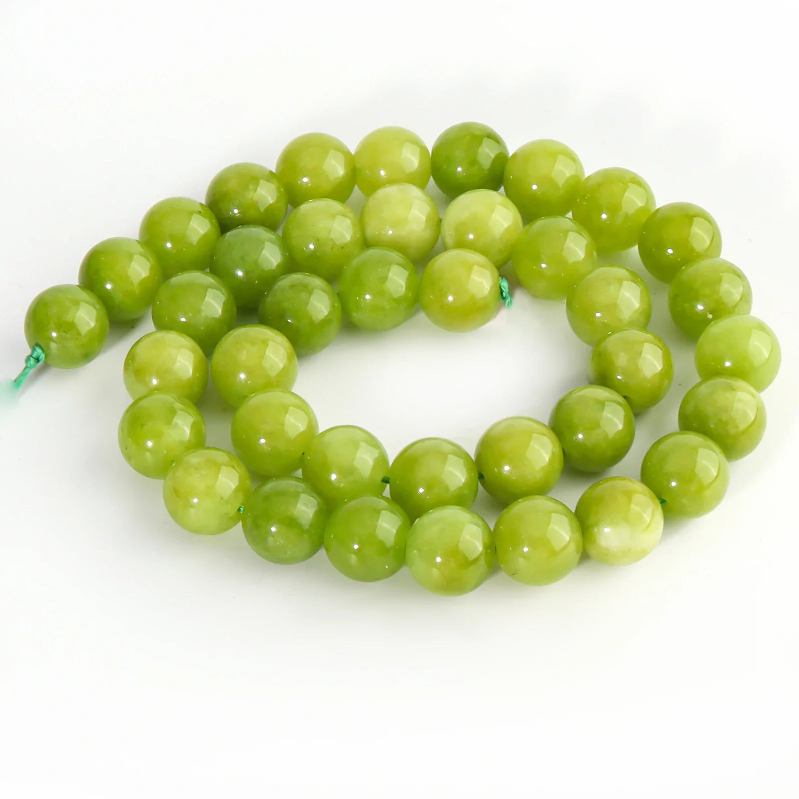 A strand of faceted green beads, likely jasper or aventurine, coiled on a plain white background.