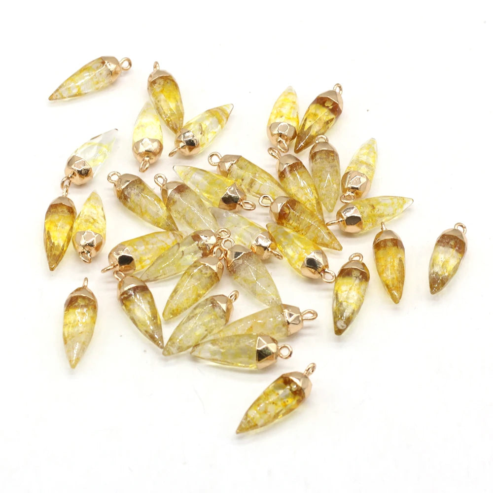 A pile of yellow faceted resin drop pendants with gold-tone metal caps and loops, arranged on a plain white background.